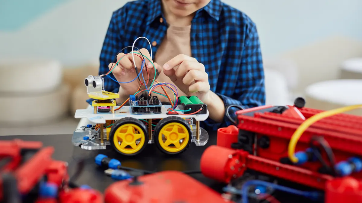 Child assembling a small robot car with wires