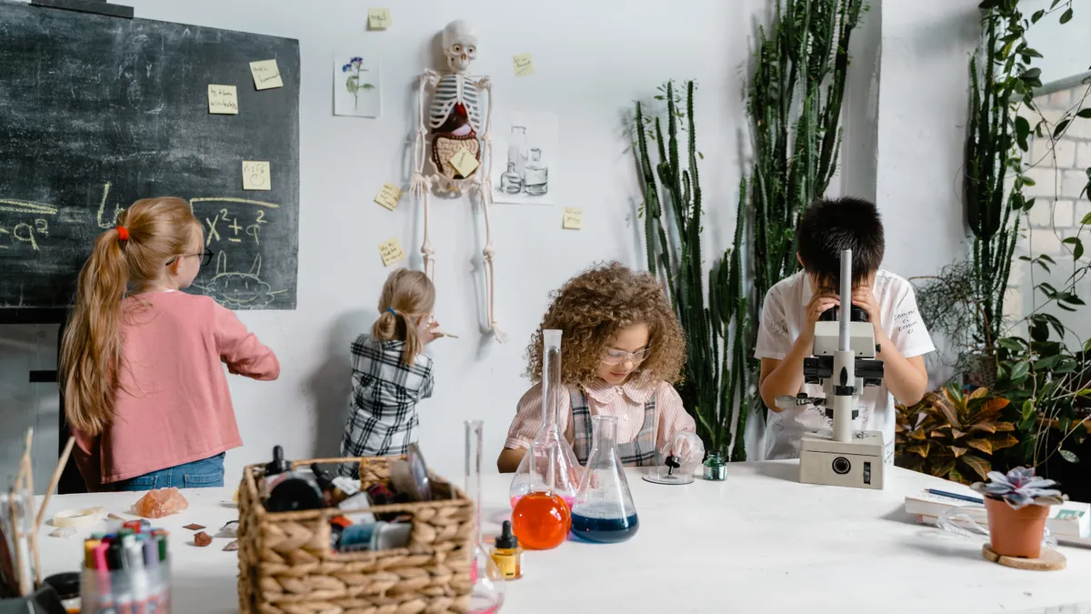 Children doing a hands-on science experiment with flasks and microscope