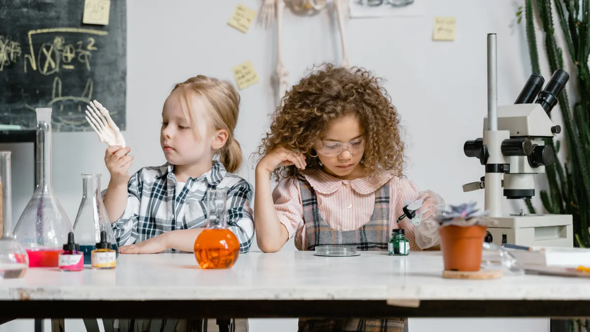 Kids at a table with beakers and a microscope